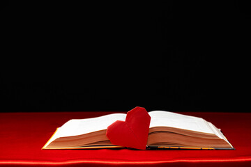 Origami paper heart and thick book on red and black background. Love for books.