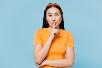 Young woman of Asian ethnicity wear orange t-shirt casual clothes say hush be quiet, finger on lips...