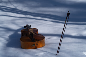 a bow and a cello discarded outdoor on the snow