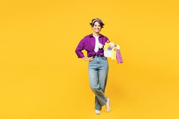 Full body young smiling happy woman wear casual purple shirt do housework tidy up hold basin with laundry clothes look camera isolated on plain yellow background studio portrait. Housekeeping concept. - obrazy, fototapety, plakaty