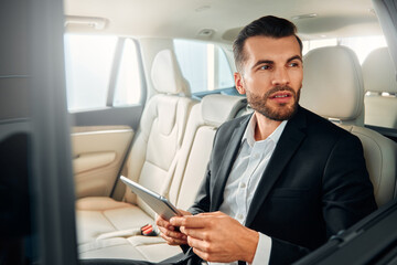 Businessman in a black suit in a car.