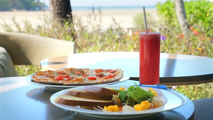 Dining setup with fresh watermelon drink and wholesome meal on seaside restaurant table. Summer vacation and outdoor dining.