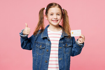 Little child cute kid girl 7-8 years old wears denim shirt hold in hand mock up of credit bank card...