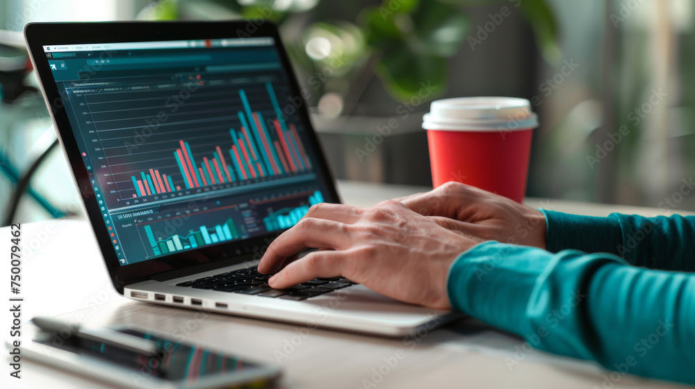 Poster close-up of a person's hand using a laptop with financial charts and graphs displayed on the screen