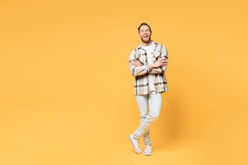 Full body smiling happy fun young Caucasian man he wear brown shirt casual clothes hold hands crossed folded look camera isolated on plain yellow orange background studio portrait. Lifestyle concept.