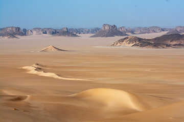 Landscape of Erg Admer in the Sahara desert, Algeria. The golden sand of Erg Admer with, in the distance, the rock formations of Tassilis. - 750080890