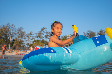 Obraz premium .A boy plays with a water gun on a blue rubber ring in the shore. .He also enjoys the feeling of the rubber ring on the blue sea, .which provides a secure surface for him to play on.