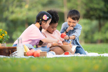 Fototapeta premium Happy family enjoying a picnic in the park, Children are having fun drawing on paper.
