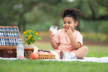 Happy family enjoying a picnic in the park, with kids drinking  milk, surrounded by nature
