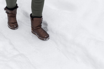 woman in solid shoes walks along a snowy path.