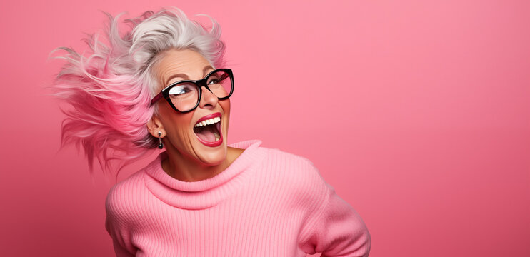Portrait d'une femme senior souriante, heureuse, portant des lunettes, sur fond rose, image avec espace pour texte.
