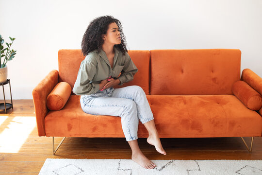 woman at home dealing with abdominal discomfort touching aching belly