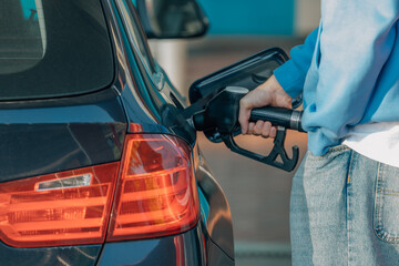 young man filling car gas tank at service station