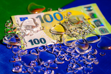 100 dollar bill on Ukrainian flag with glass hearts.