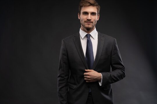 Portrait of handsome man in black suit on dark background.