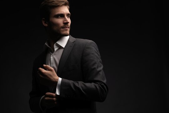 Portrait of handsome man in black suit on dark background.