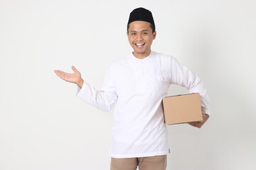 Portrait of attractive Asian muslim man in koko shirt with peci pointing to the side while carrying...