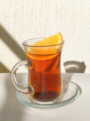 black tea with lemon in a glass cup and saucer in the sunlight