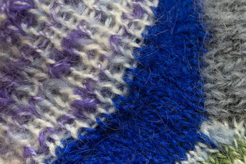 Texture of a knitted element of a blue, melange and gray wool sock close up.