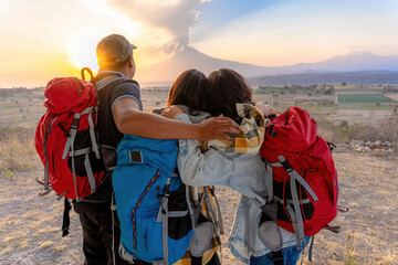 Moment of contemplation: sportsmen watching the sunset in the mountains in the background an active volcano.concept:hiking, freedom, travel, exploration, summit, walking. © Nailotl