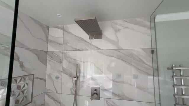 Waterfall type shower faucet running in large master bathroom shower stall  
