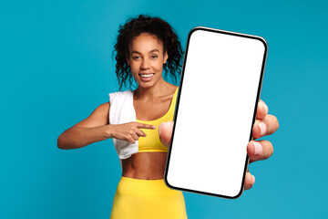 Athletic African lady shows phone makes thumbs up, blue background
