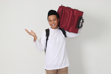 Portrait of excited Asian muslim man carrying suitcase pointing with hand to the side. Going home...