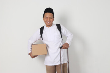 Portrait of excited Asian muslim man in koko shirt with peci carrying cardboard box and holding...