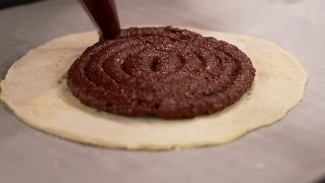 the pastry chef completes the dessert with a chocolate garnish using a piping bag
