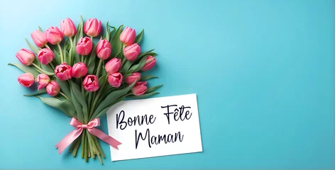 Fotobehang Un bouquet de fleurs avec des tulipes, un ruban rose et une carte où il est écrit bonne fête maman sur un fond turquoise © infographiste06