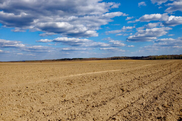 Open farmland with rich soil and a cloud-filled sky.