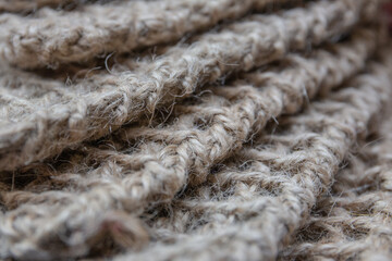 The interesting texture of jute knitted elements in the natural color of wood, shot using macro photography, are located diagonally in the frame.