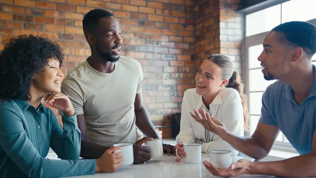 Multi-Cultural business team taking coffee break in kitchen area of modern open plan office together - shot in slow motion