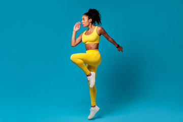 African American sportswoman doing elbow to knee standing pose, studio