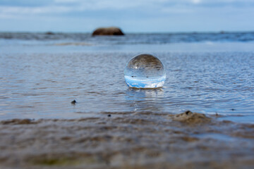 Beach and sea reflected in a sphere lying  in the water