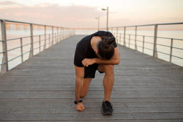 guy takes rest bent over in exhaustion after jog outdoor
