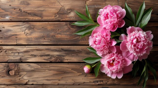 a bouquet of pink flowers sitting on top of a wooden table next to a green leafy plant on top of a wooden table.
