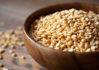 Organic Dried Yellow Split Peas in a Wooden Bowl. Uncooked Raw Legume Concept.