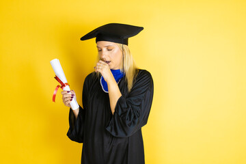 Beautiful blonde young woman wearing graduation cap and ceremony robe with her hand to her mouth because she's coughing