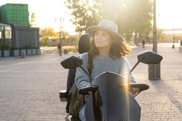 Woman tourist riding a four wheel mobility electric scooter on a city street