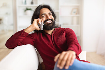 Closeup of cheerful indian guy have phone conversation at home