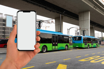 A hand with a phone on the background of a charging electric bus.