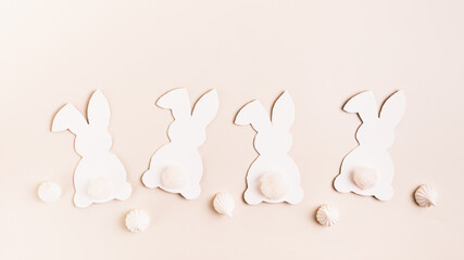 Happy Easter white decorative bunnies and mini meringues on pink background top view web banner