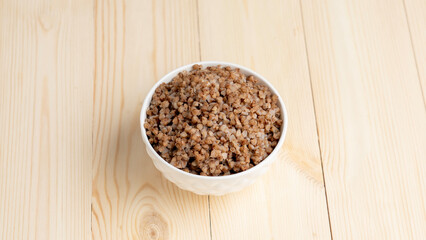 boiled buckwheat porridge in a cup on a wooden background. dietary products, lean food without animal fats,