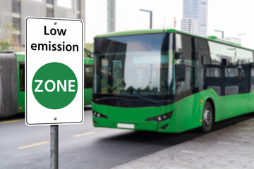 Road sign "Low emission ZONE" on a background of green electric buses. Clean mobility concept