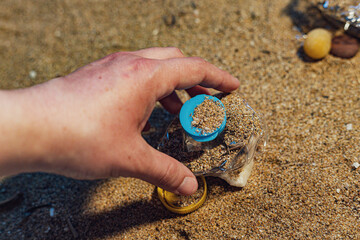 Person picking up trash with a bare hand on a beach