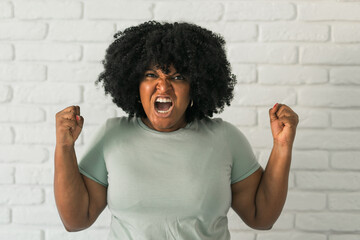 Angry african american woman screaming on brick background. Bad aggressive emotions and...