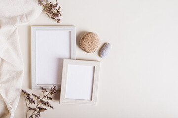 A pair of empty photo frames, dried flowers and a stone on a light background