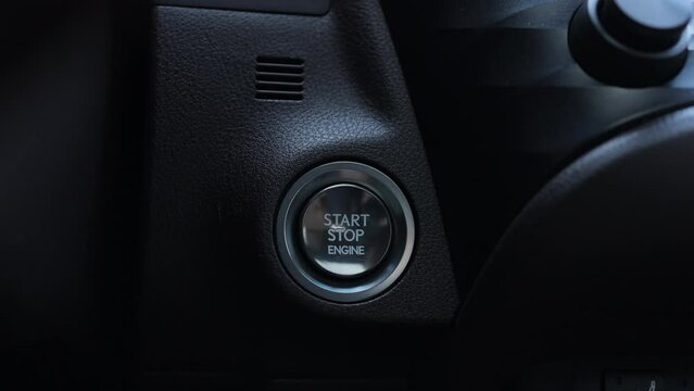 Finger press the button to start the car engine. The driver's hand is pressing the car start button. Starting car engine. Track in to the button. Concept of transportation and technology.