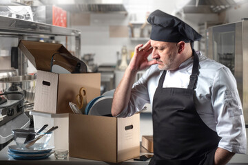 Owner of bankrupt restaurant. Man cook is broke. Culinary man with boxes stands in kitchen. Chef...